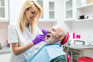 Implant dentist in Fort Worth examining a patient’s mouth