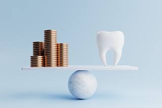 A balance beam supporting a model tooth and stacks of coins