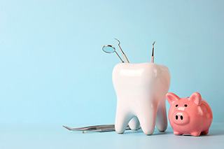 A ceramic model of a tooth and a piggy bank against a blue background