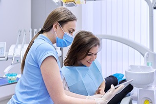 A young woman paying the cost of cosmetic dentistry