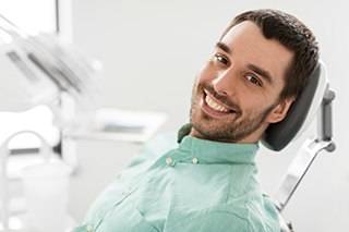 a patient smiling and holding a mirror